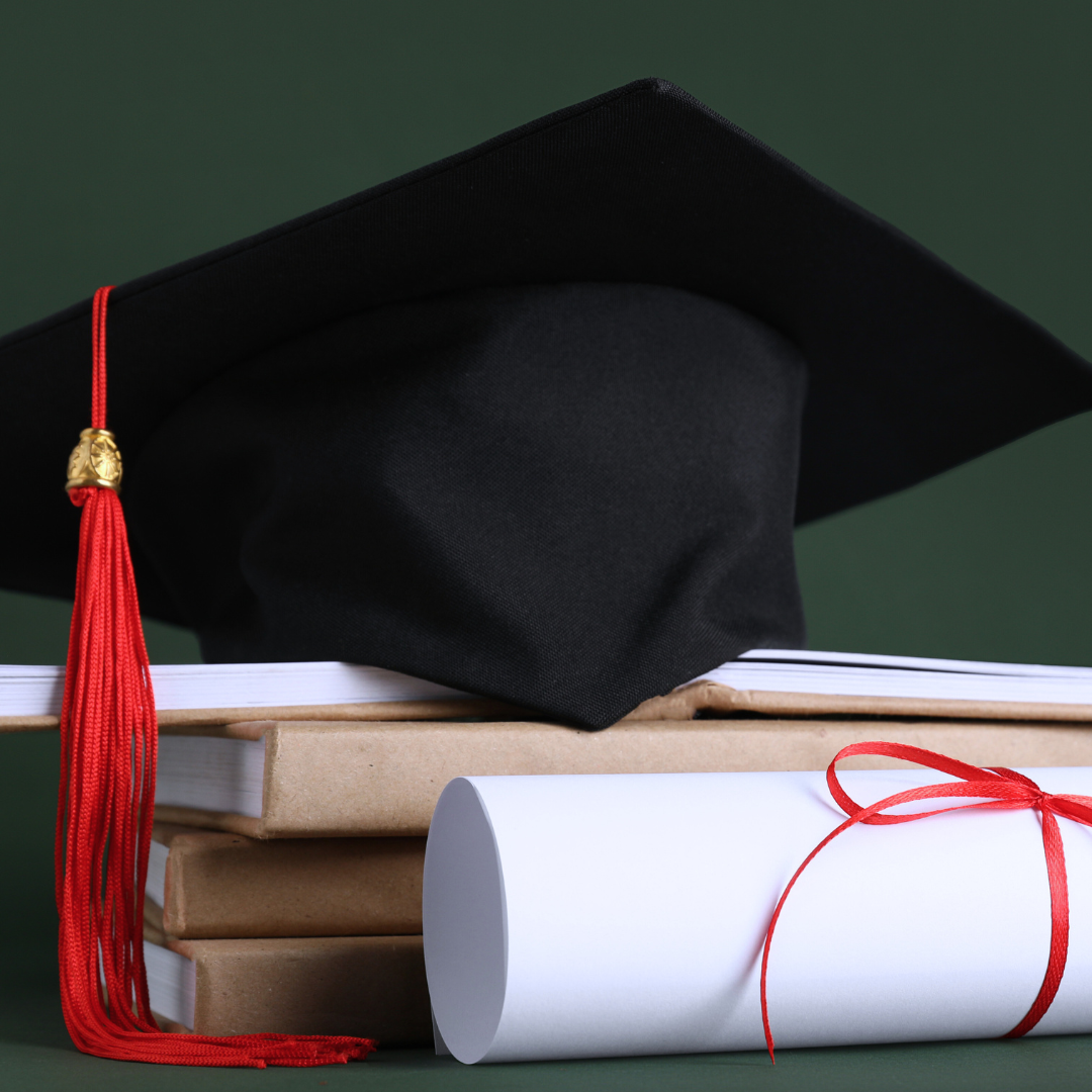 Graduation cap on top of book subscription books and rolled diploma with red ribbon on a green background